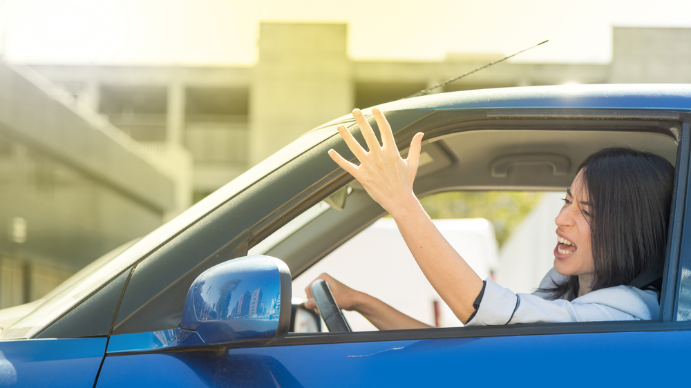 angry woman in a car throwing her hands out the window and shouting