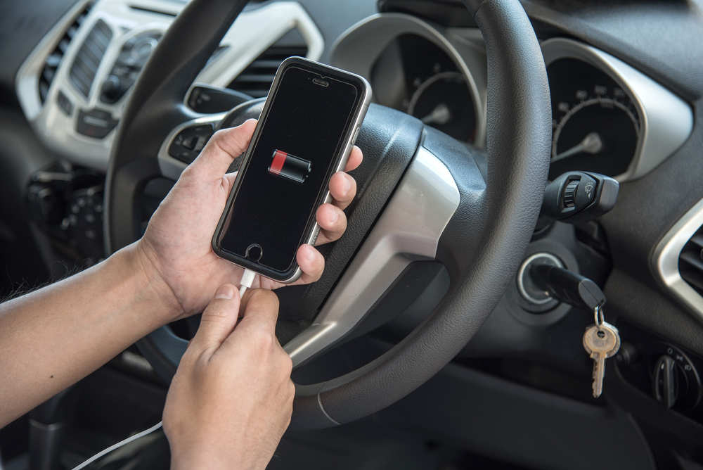 person charging their phone with a portable charger in their car