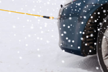 car being towed in the snow zoomed in on the rope