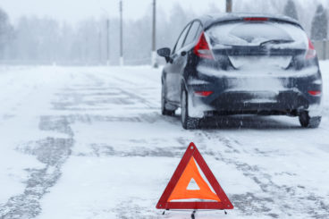 car stuck in snow with a warning triangle