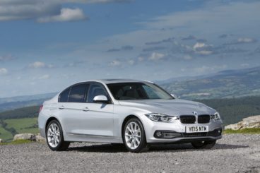Silver BMW 3 Series parked on a hill top with the countryside in the background