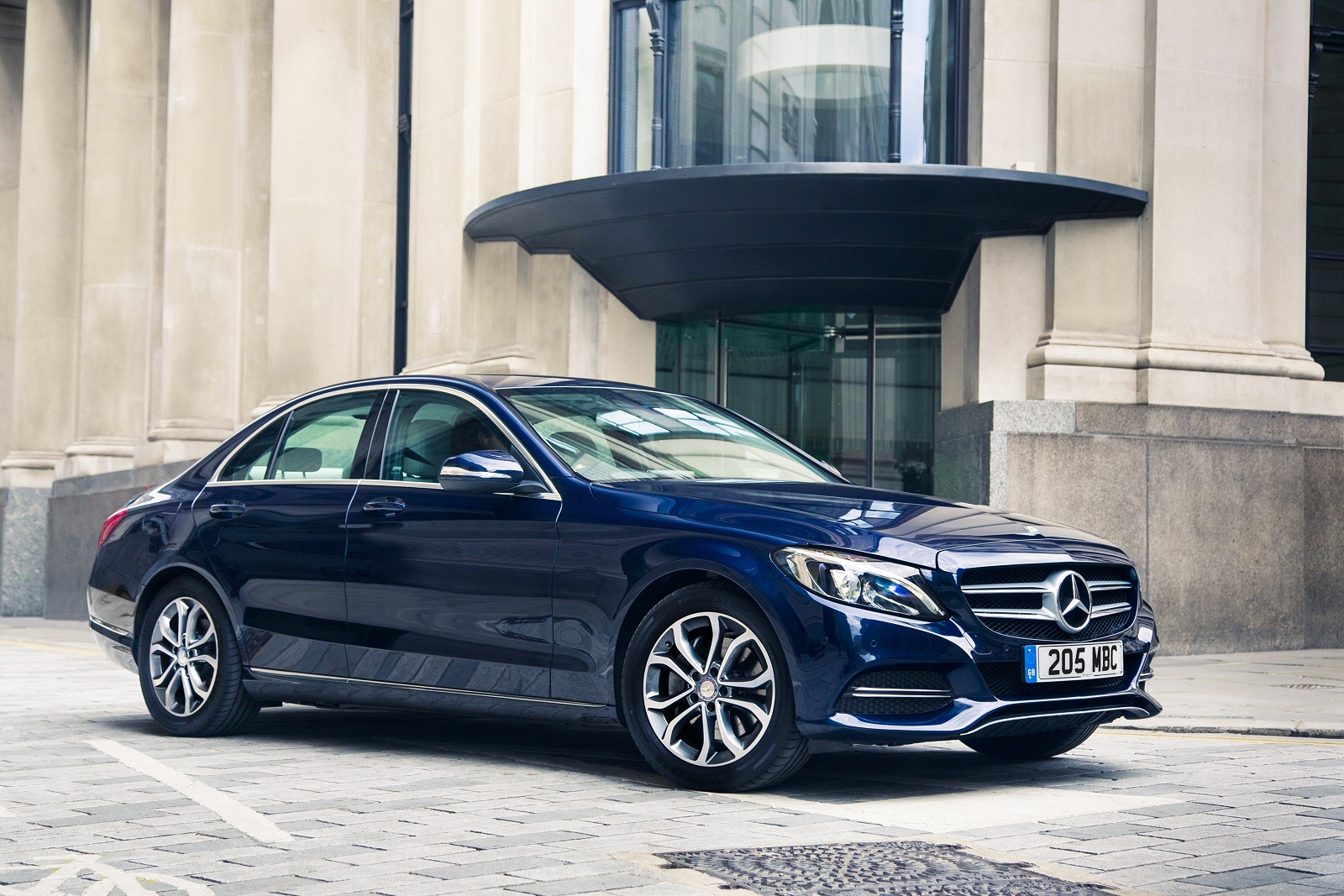 dark blue Mercedes C Class parked on street next to smart building