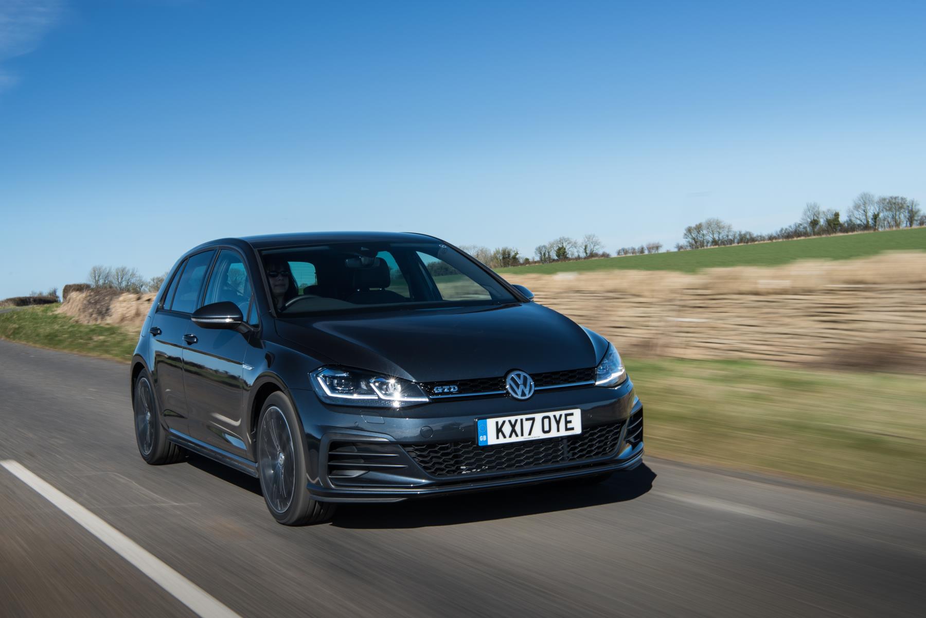 dark coloured Volkswagen Gold GTD driving down a road