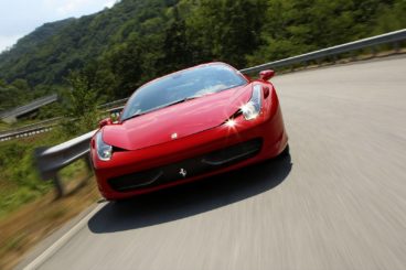 red Ferrari 458 Italia on the road in the mountains turning a corner