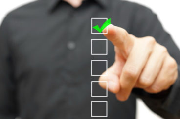 man in a black shirt touching a touchscreen of a green tick in a box
