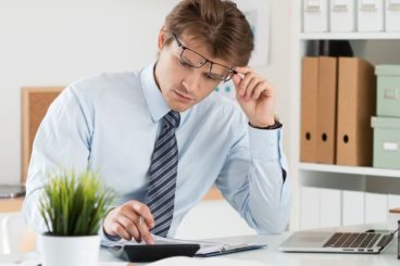 Business man wearing glasses and using a calculator - mileage