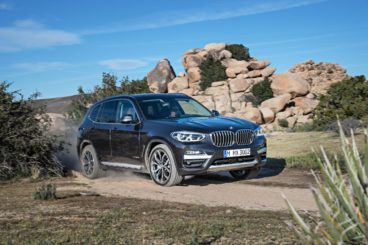 a blue coloured BMW X3 Estate driving quickly in a dessert setting