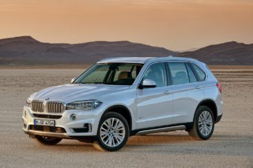 metallic white BMW X5 parked in dessert with mountains in the background