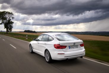 White bmw 3 series gran turismo driving away with cloudy weather in