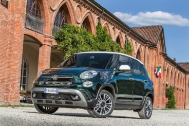 metallic fiat 500l Hatchback parked on gravel in fount of vintage building