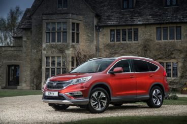 metallic red honda crv parked on gravel in front of country house