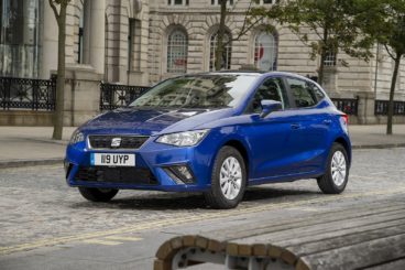 a bright blue seat ibiza parked on brick road with buildings in the background