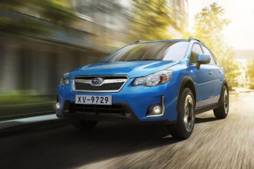 bright blue subaru xv hatchback driving on tarmac road with blurred background