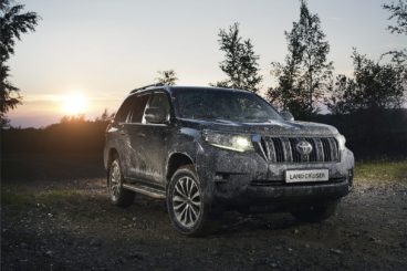 a muddy toyota land cruiser parked in forest setting at sun set