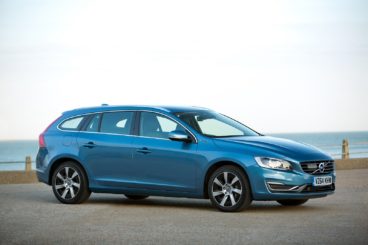 metallic blue volvo v60 parked in front of beach scene