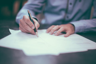 man in a blue shirt signing a contract