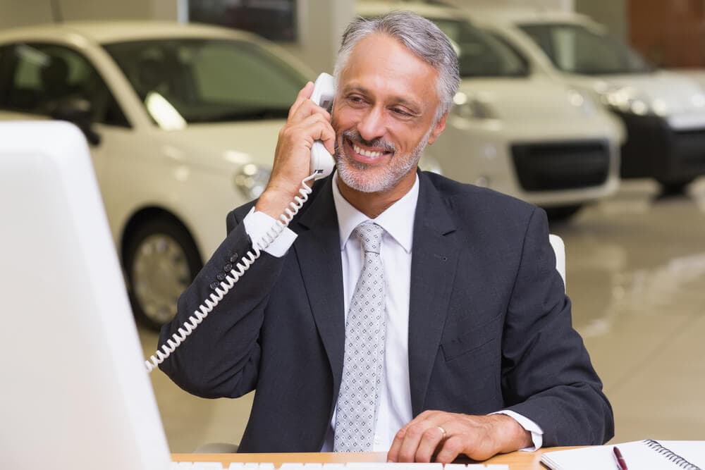 Gentleman on phone in car dealership