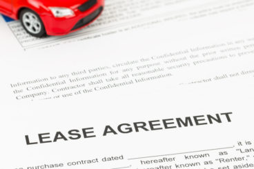 Red toy car on top of lease agreement