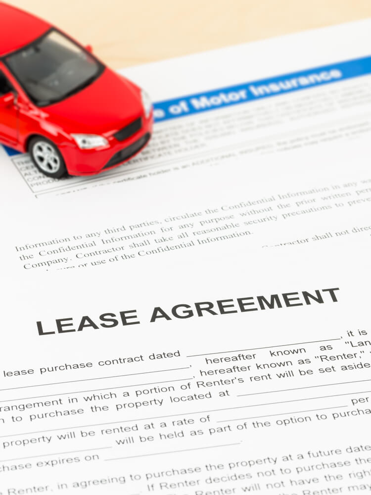Red toy car on top of lease agreement
