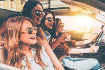 young women wearing sunglasses smiling in a car