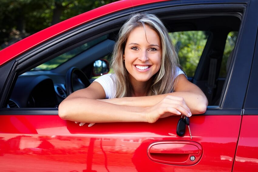 Lady leaning out red car, holding the keys