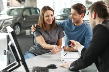 people at car dealership exchanging keys