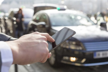 Man pointing at phone with taxi in background