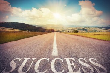 Image of a road leading off in to the sunset with the text Success overlayed.