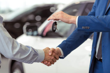 Two man shaking hands, handing our car keys - First Car