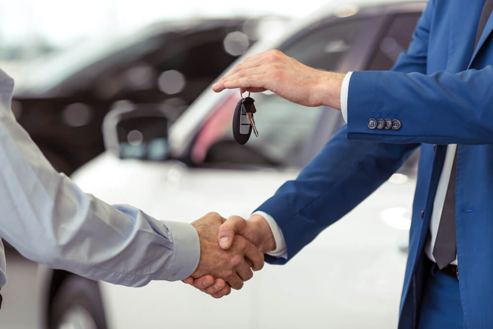 Two man shaking hands, handing our car keys - First Car