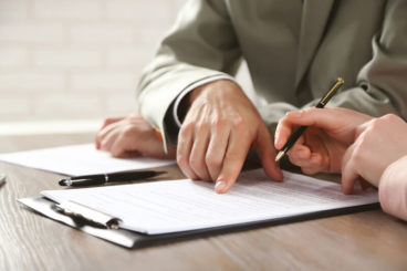 man pointing at a part in the contract with another person