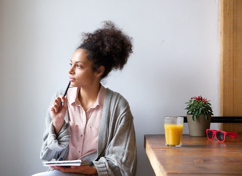 Woman starring in to the distance with pen resting on chin