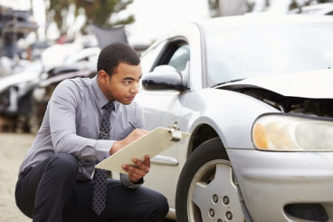 man inspecting a car with a clipboard