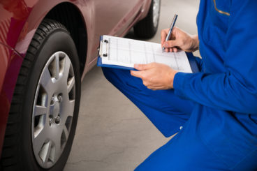 mechanic inspecting a car with a clipboard