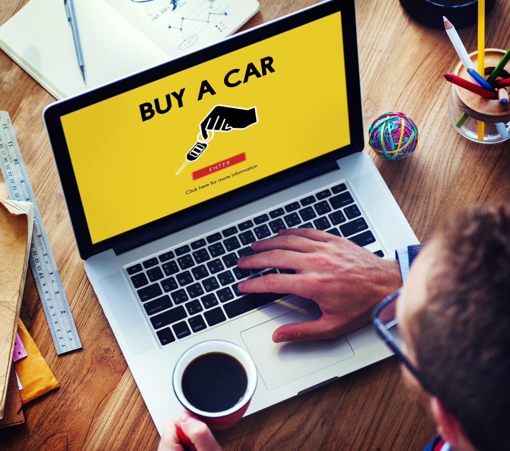 picture of a man on a laptop with a coffee with the screen saying buy a car