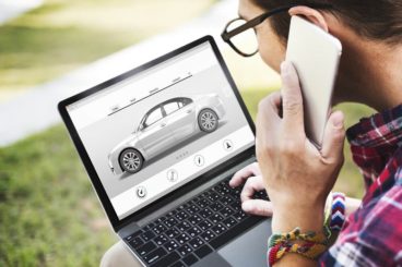 man on the phone with a laptop looking ta a car deal