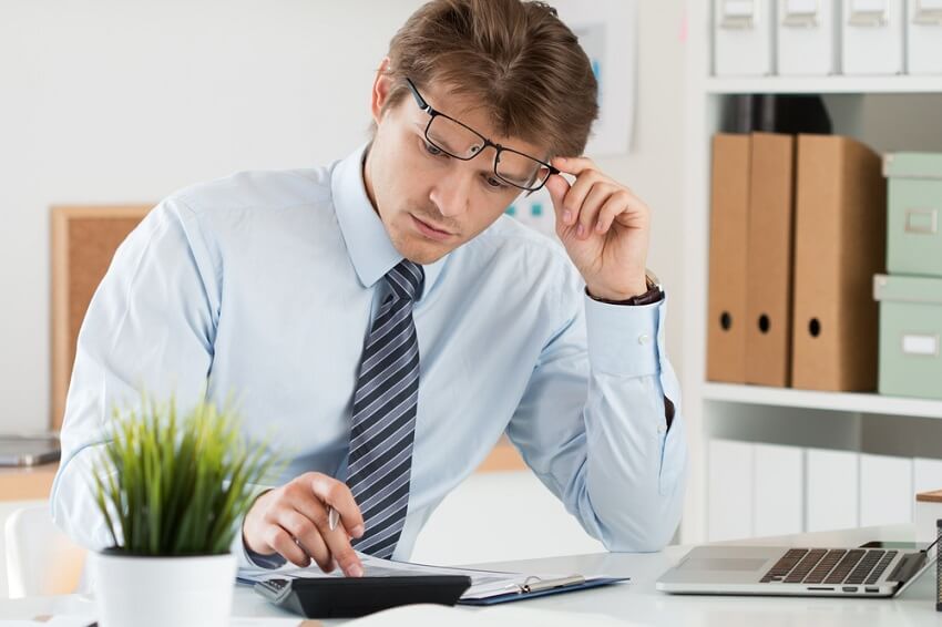 business man with a calculator and a laptop on a desk