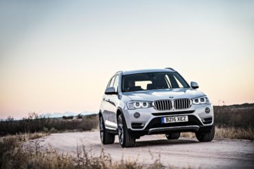Silver BMW X3 driving off-road with grass on the banks