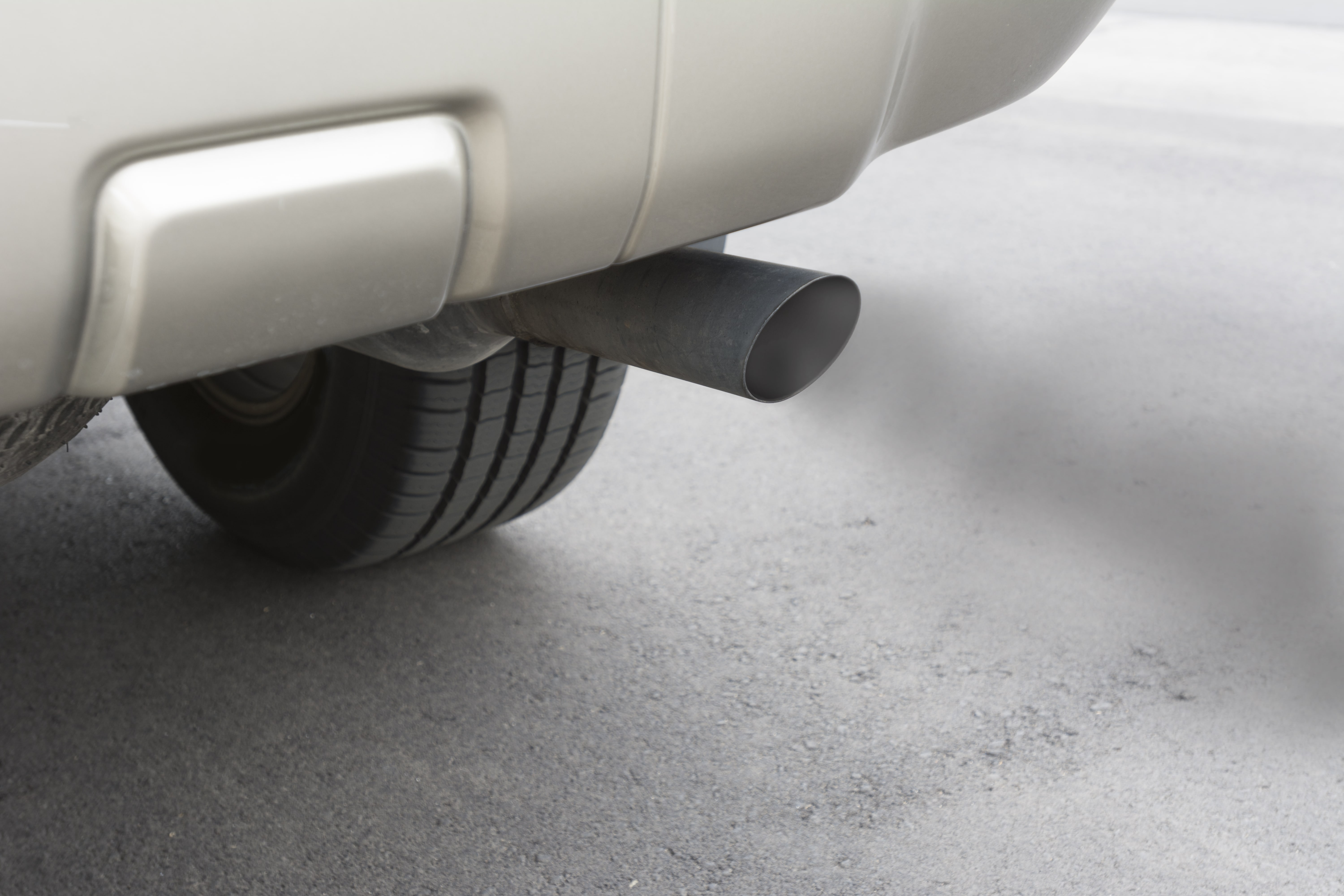A car emits carbon monoxide gas from its exhaust tailpipe, showing how pollution is formed.