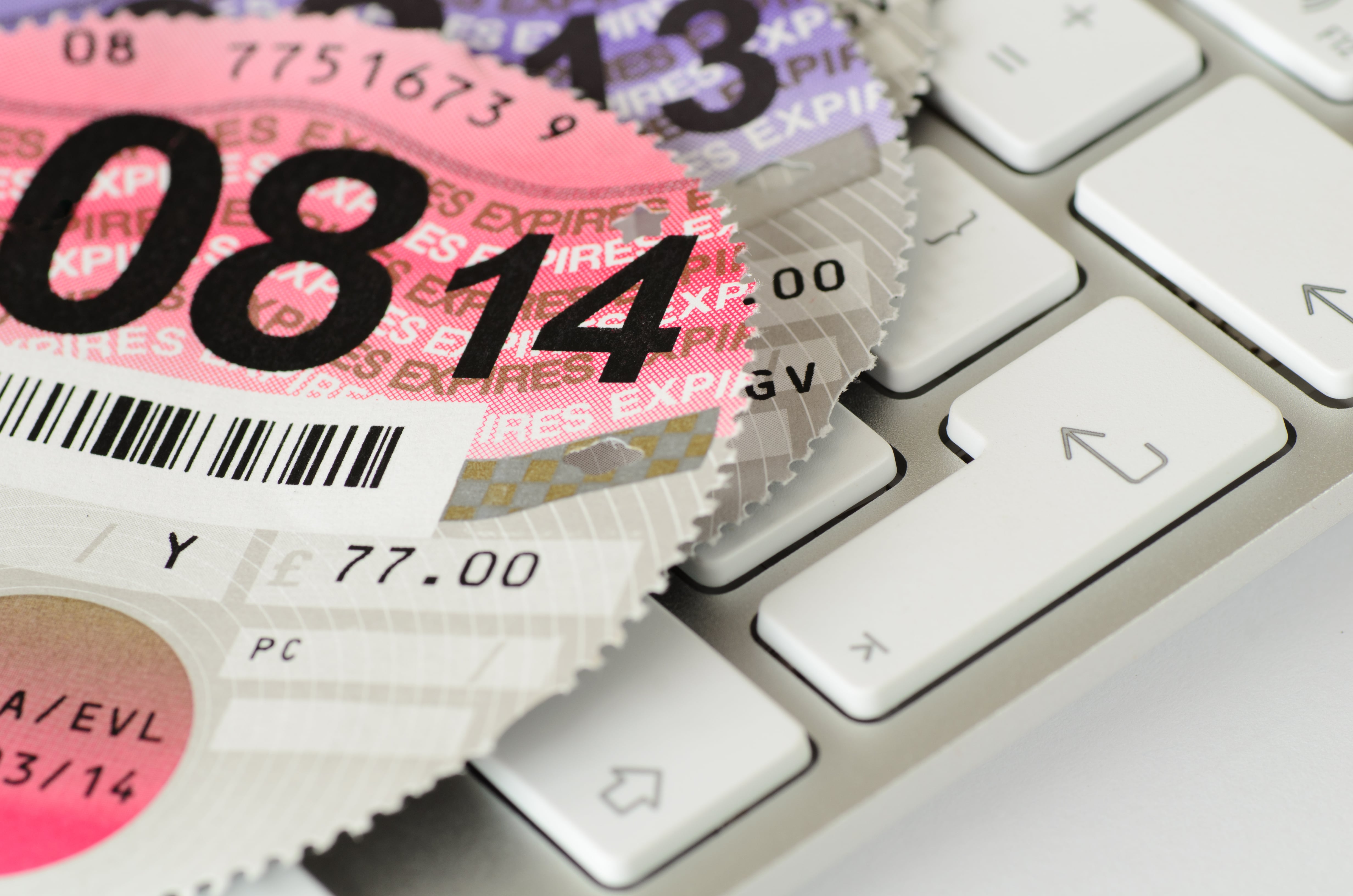 Expired UK vehicle tax disc on a keyboard.