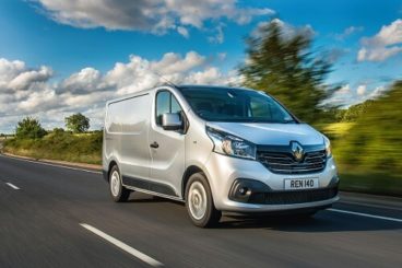Silver Renault Trafic driving on a country road with trees in the background