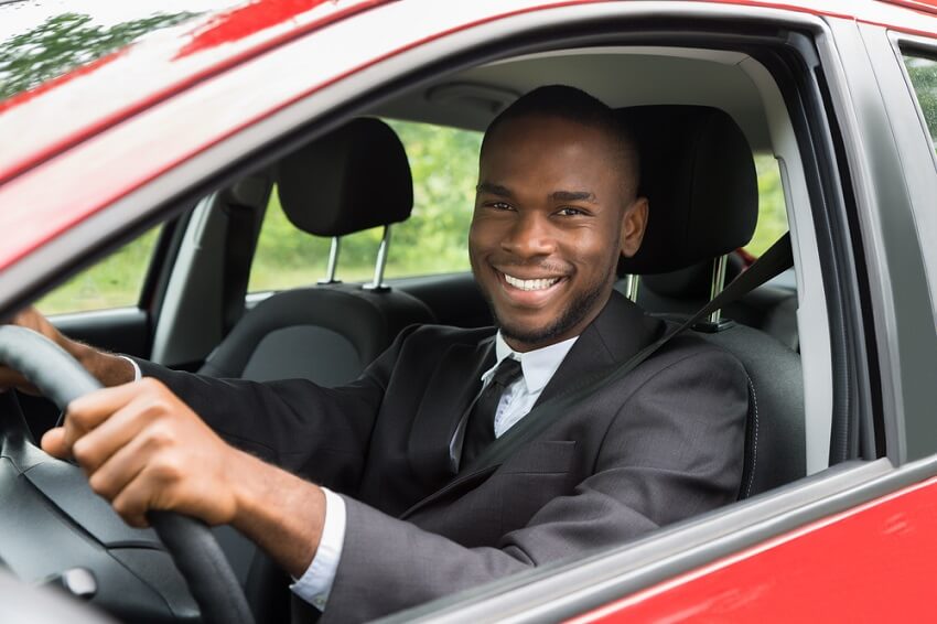 Smiling man driving a red car