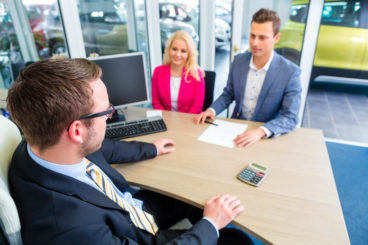 people at a dealership discussing new car purchase