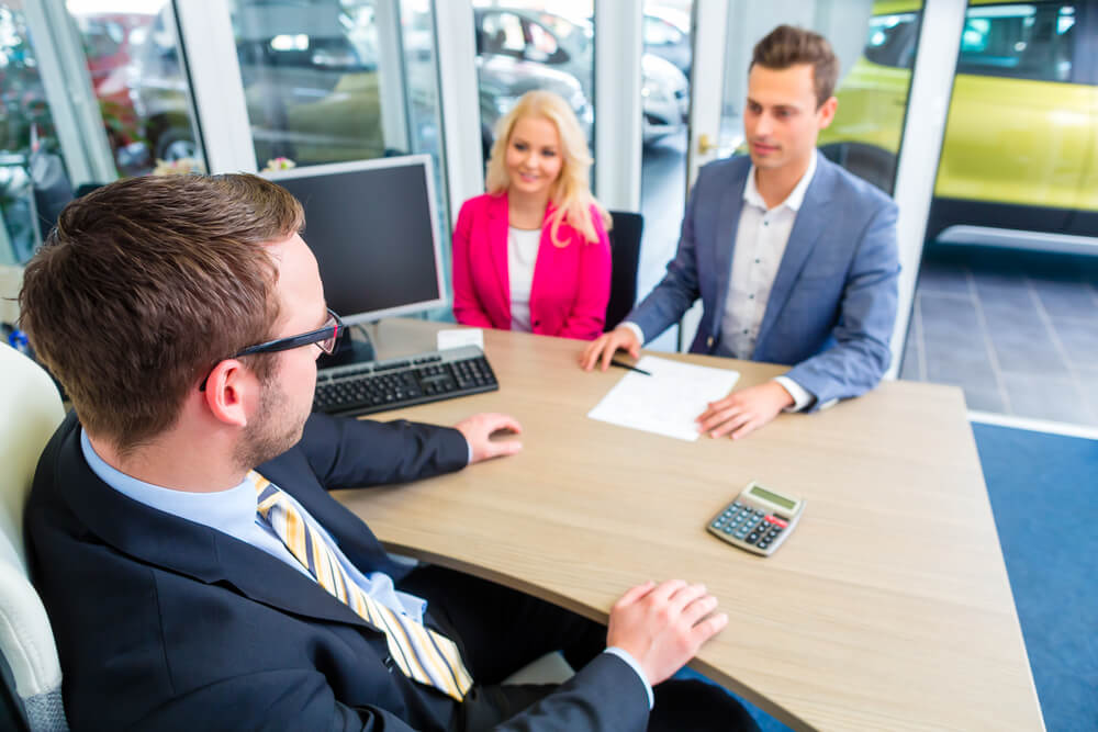 people at a dealership discussing new car purchase