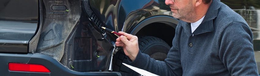 man inspecting car with a clipboard