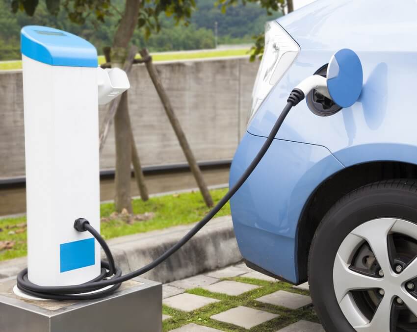 blue car parked being charged up by an electric charging point