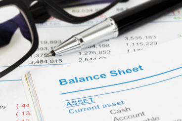 balance sheet with asset written on it with glasses and a pen resting on the paper