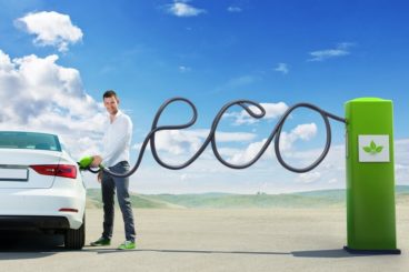 Man filling up his car with fuel hose spelling eco - is an electric car worth it?