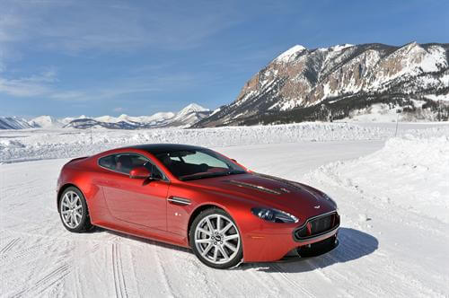 Red 2017 Aston Martin V12 Vantage Coupe front on snow with mountain backdrop