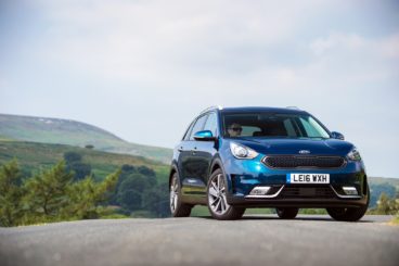 Blue Kia Niro parked on a hill with the countryside in the background